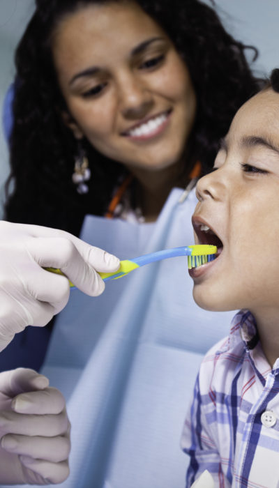 Dentist teaching toothbrush use to child patient